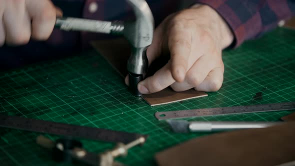 The Process of Manufacturing a Leather Wallet Handmade. The Craftsman Cut Off a Piece of Leather