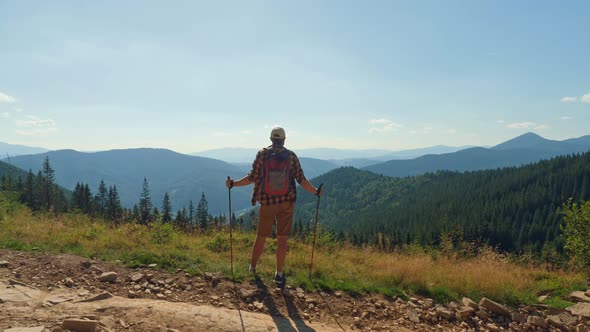 Man with Trekking Poles Standing on the Top of the Mountain