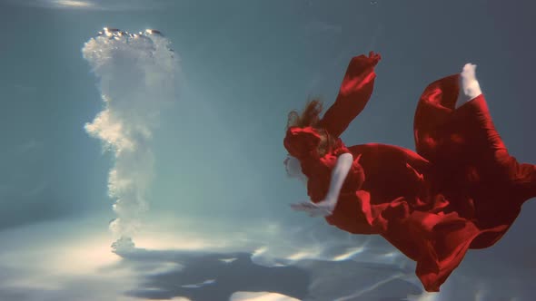 Attractive Redhaired Young Woman Swims Beautifully Underwater in a Red Dress alt