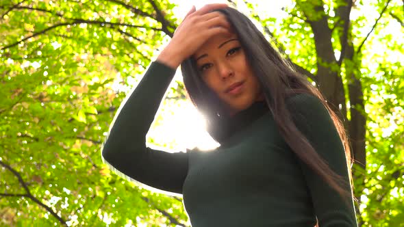 A Young Asian Woman Strikes Poses for The Camera in A Park alt