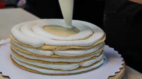 The Pastry Chef Applies Cream to a Multilayered Cake and Equalizes with a Knife alt
