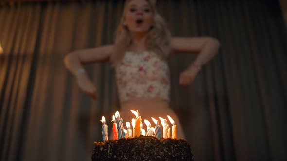 Beautiful Woman Blowing Out Candles on a Festive Cake. alt