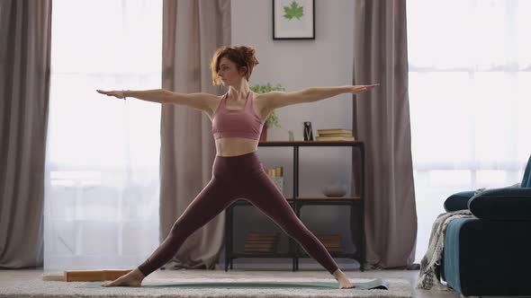 Sportswoman is Performing Yoga Asana at Home Training Alone in Living Room at Morning Keeping Fit alt