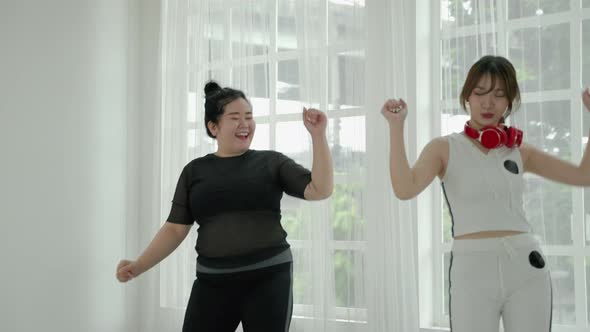 beautiful Asian woman and fat woman practicing dancing in the room cheerful and happy. Concept of ex