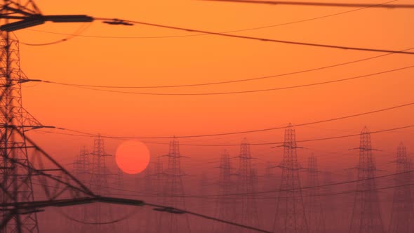 Loopable shot of high voltage electricity pylons during sunset. Bright red sky, alt