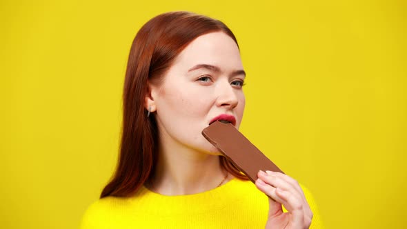 Portrait of Gorgeous Confident Redhead Woman Biting Chocolate Bar and Chewing Sweet Delicious alt