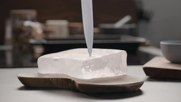 Slow Motion Man Breaking Ice Block with Knife on Olive Wood Board alt