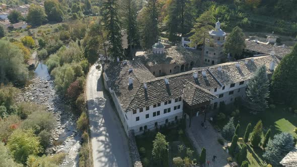 Drone view, above the third largest Troyan Monastery with a river alongside. Bulgaria alt