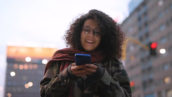 Slow motion young multi ethnic woman outdoor using smart phone laughing alt