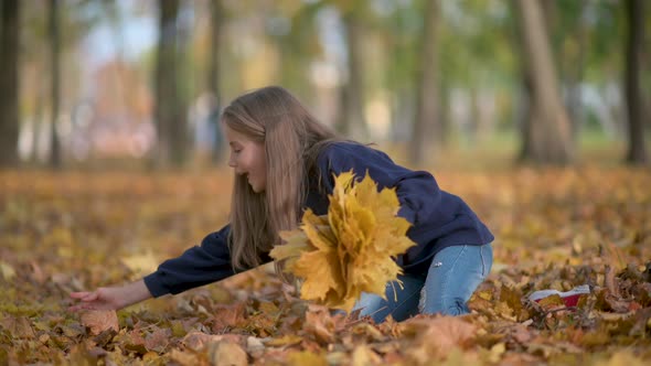 Happy Girl in Coat Walks in a Sunny Autumn Park. alt
