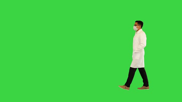 Confident Ethnic Doctor in Surgical Face Mask Walk Holding Hands in Pockets of White Medical Coat on