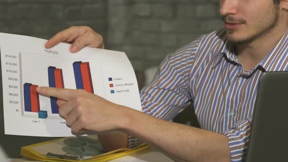 Cropped Shot of a Businessman Showing Printed Diagrams on a Business Meeting