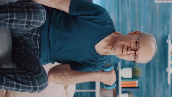 Vertical Video Handheld Shot of Old Man Lifting Weights and Training alt