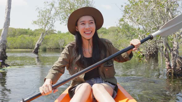 Asian young attractive tourist woman rowing kayak alone in forest lake. alt