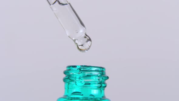 A Drop of Essential Oil Falls From the Pipette Into the Cosmetic Bottle Macro alt
