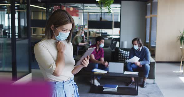 Asian businesswoman wearing face mask using digital tablet modern office alt