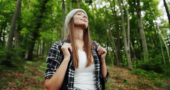 Woman with Backpack Smelling Fresh Air in Forest