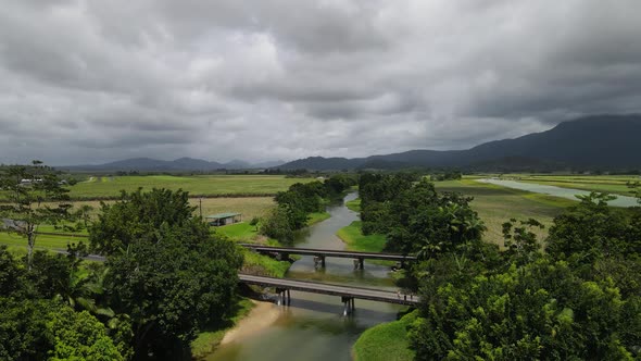 Aerial view looking down at a small country road bridge spanning over a crocodile in infested river alt