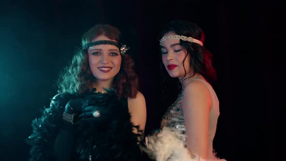 Attractive Flappers Women Dressed in Roaring Twenties Time Dancing on Party in Neon Smoke Room alt