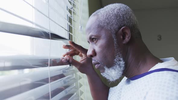 African american male patient looking at window in hospital room smiling alt