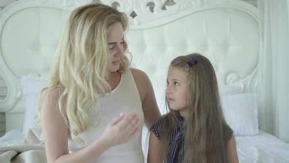 Positive Pregnant Mother Talking with Daughter and Hugging Child. Portrait of Happy Caucasian Parent alt