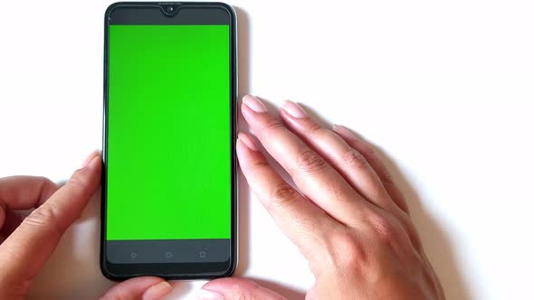 Women's Hands are Correcting a Smartphone on the Table with a Chroma Key Screen