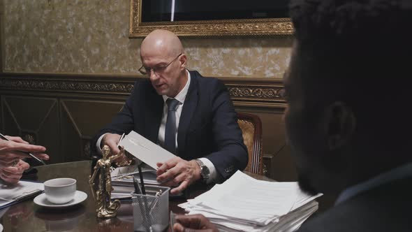 Lawyer Going through Paperwork and Talking with Colleagues at Meeting alt