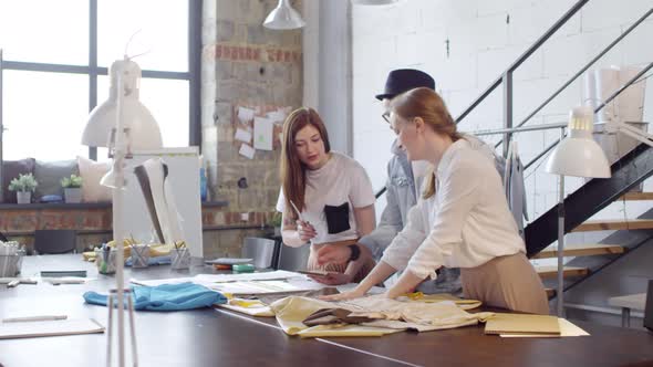Team of Dressmakers Discussing Fabric in Sewing Studio alt