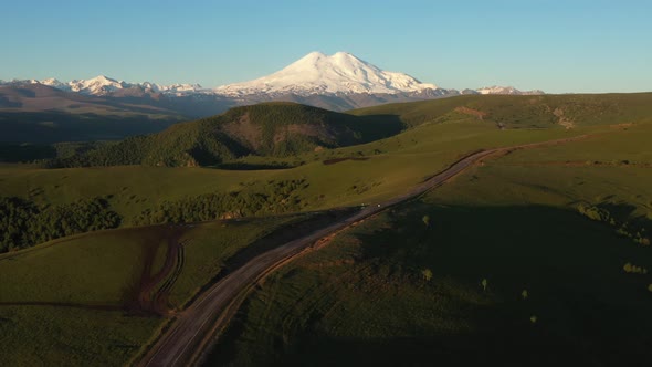 Top view of green field, winding roads and Caucasus mountains.Sunrise above Mount Elbrus