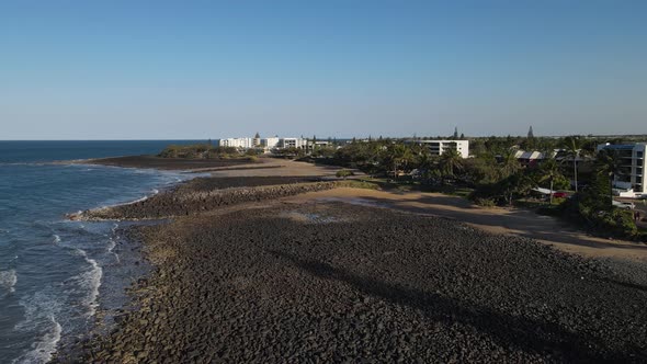 A high revealing drone video showing the raw rocky coastline of the small town of Bargara located in alt