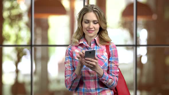 Young Girl in Casual Cloth and Purse Entartaining with Social Media on Phone alt
