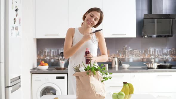 Young Beautiful Caucasian Female Standing on Kitchen Drinking Tomato Juice From Bottle Enjoying It alt