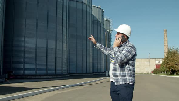 Engineer Talking on Phone Near Grain Elevator