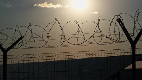 Barbed Wire Fence Around the Solar Power Plant During Sunset alt