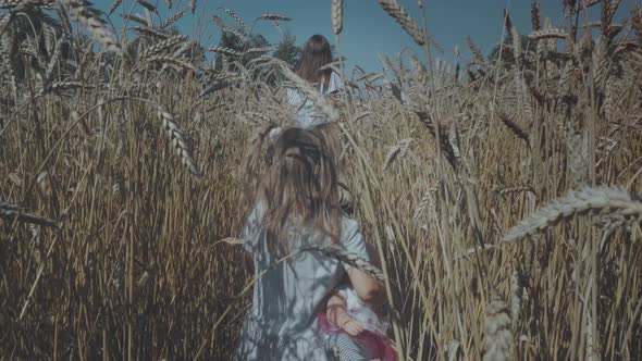 Woman with two kids walking through wheat field alt