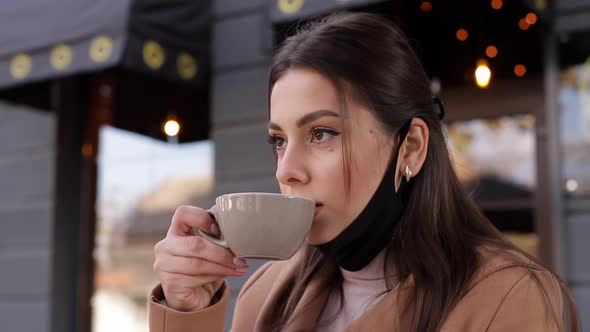 Process of Beautiful Woman Takes Off Protective Mask for Drinking Coffee. Female Sitting Outdoors on