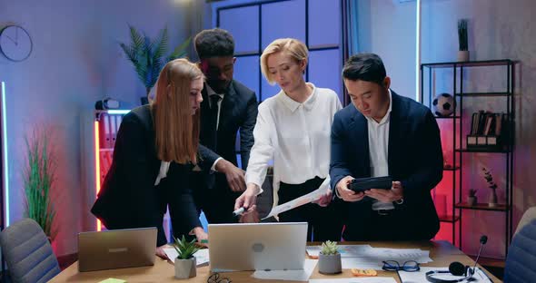 Businesspeople Working Together with Paper Reports and Information on Laptop and Tablet Device alt