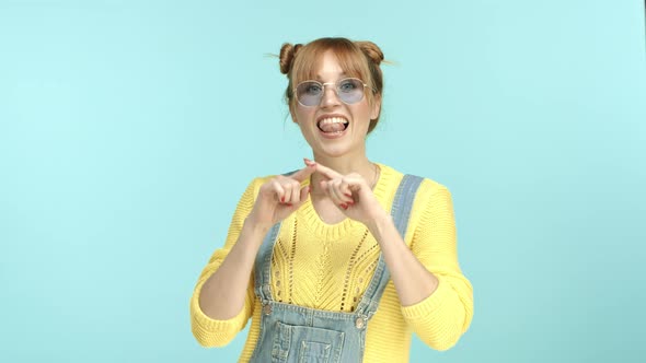 Beautiful Funky Girl in Sunglasses and Overalls Drawing Heart Shape in Air and Saying I Love you