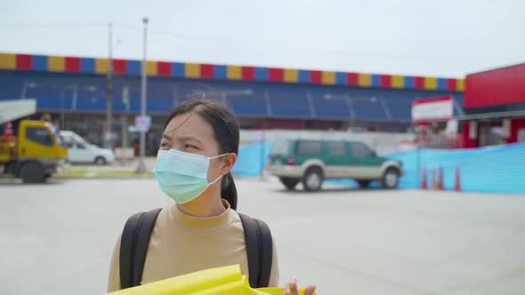 Asian woman wearing protective face mask walking at city street.