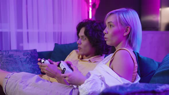 Young Couple Woman and Man Inside of Room Exited Look on a Tv Screen Playing Video Games at Home alt