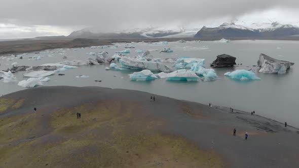 Aerial Shot of Tourists Viewing a Glacial Lagoon. alt