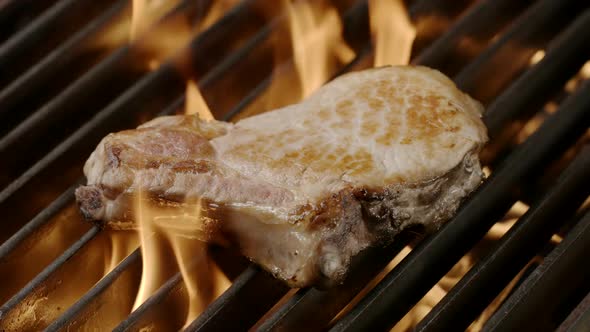 Pork steak is grilled in a flame
