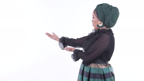 Happy Young African Muslim Woman Showing To the Back and Looking Surprised alt