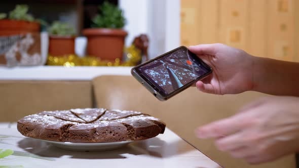 Female Hands Shoots Video of a Chocolate Pie in Kitchen on a Smart Phone alt