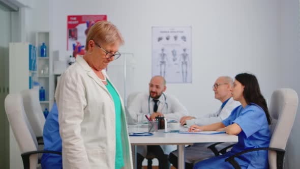 Portrait of Elderly Doctor Standing in Front of Camera Smiling alt