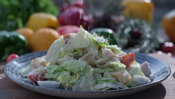 Closeup of Coarsely Chopped Caesar Salad with Chicken Fillet in the Ceramic Dish is is Sprinkled alt