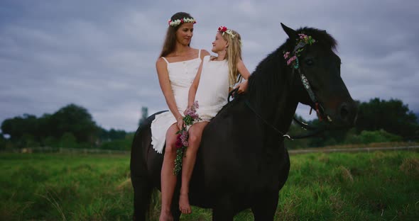 Happy woman and flower girl riding horse together alt