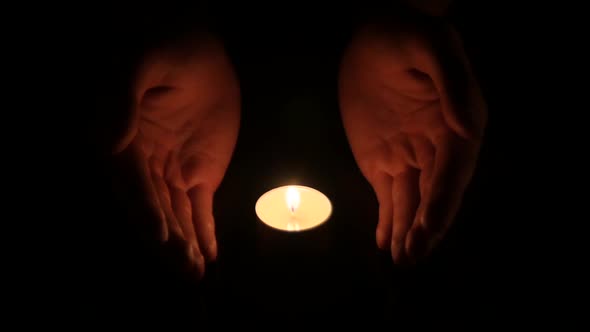 Hands Holding a Burning Candle in Dark alt