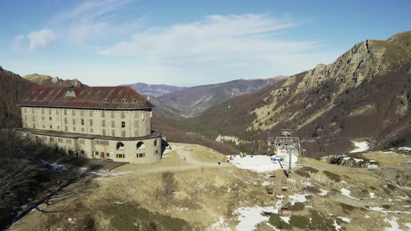 Aerial, Alps Mountains Partially Covered With Snow In Italy And A Chairlift With Skiers