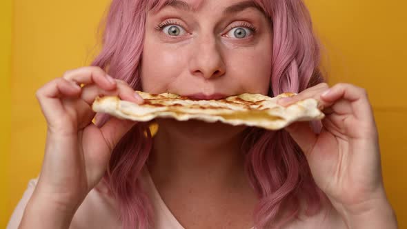 Happy Hungry Positive Girl Eating Delicious Pita Bread with Cheese Filling on a Yellow Background